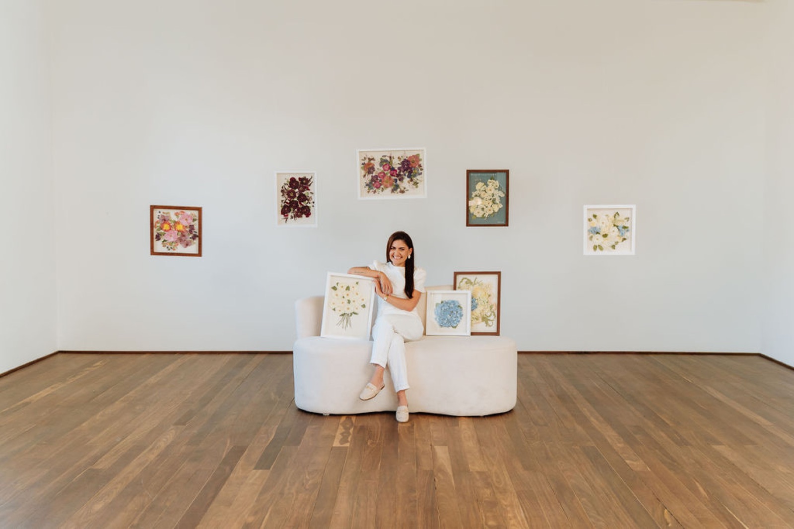 Magda no ateliê, com os quadros na parede